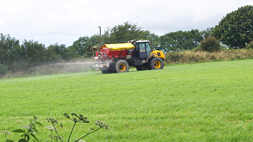Tractor spreading fertiliser on grassland