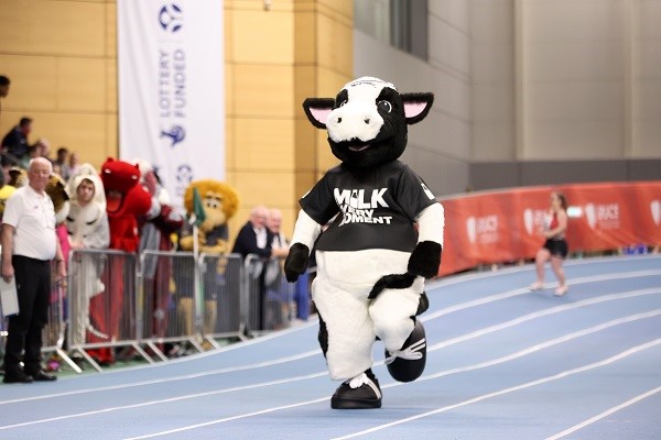 The Milk Every Moment mascot Moovit the Cow running down a track.