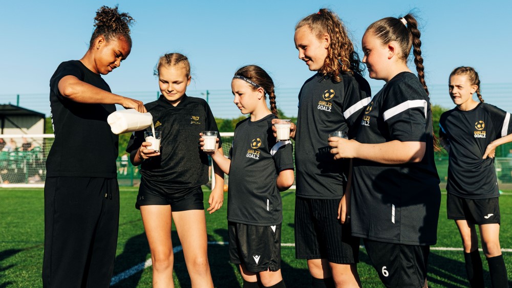 Nikita Parris pouring young players a glass of milk