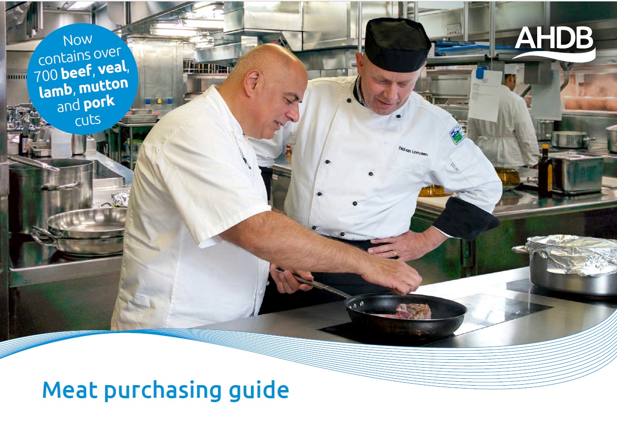 Two cooks in a kitchen cooking meat in a frying pan. 