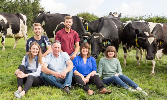 a group of people posing for a photo in front of a herd of cattle