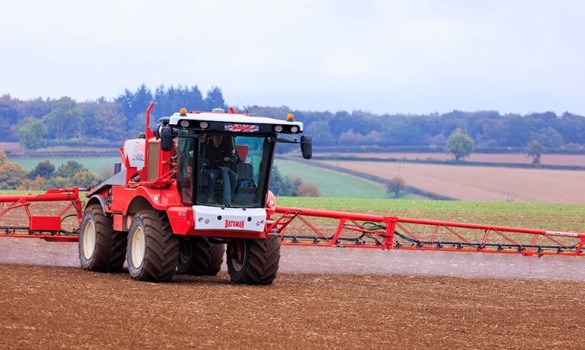 A red tractor ploughing a field.