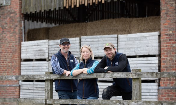 Three farmers form Altcar Moss Monitor Farm stood behind a fence.