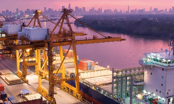 A cargo ship laden with containers at a port in semi-darkness.