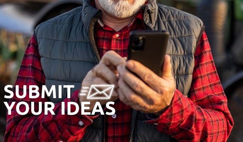 Man typing on phone behind text that reads 'submit your ideas'