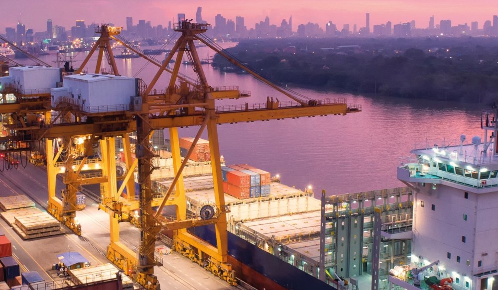 A cargo ship laden with containers at a port in semi-darkness.